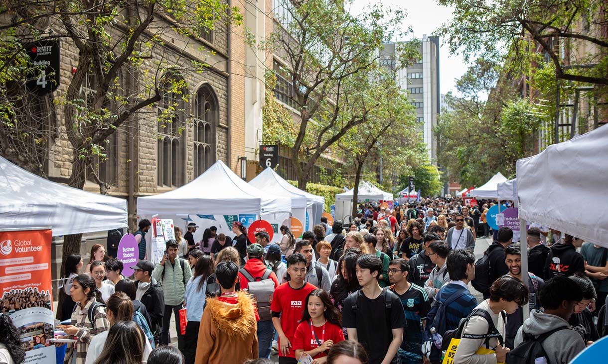 Large crowd on street lined with stalls.