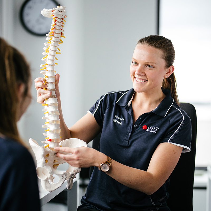 A woman holding an example of a human spine bone