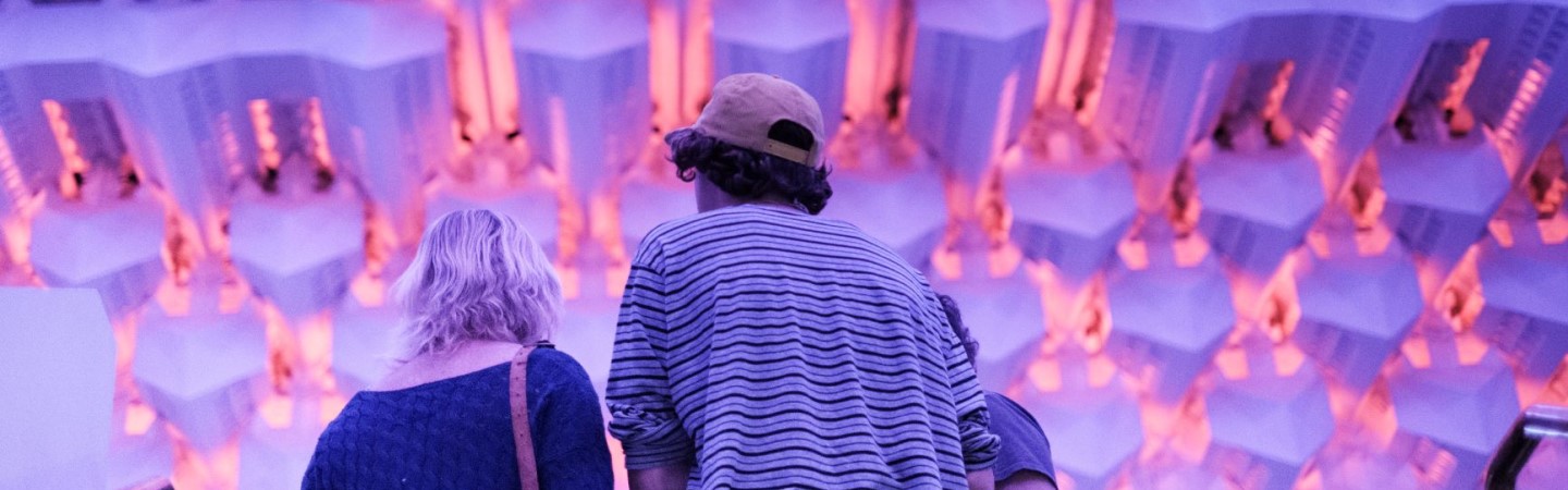 Two visitors arrive in the theatre at The Capitol, the ceiling is lit up in purple and peach colours