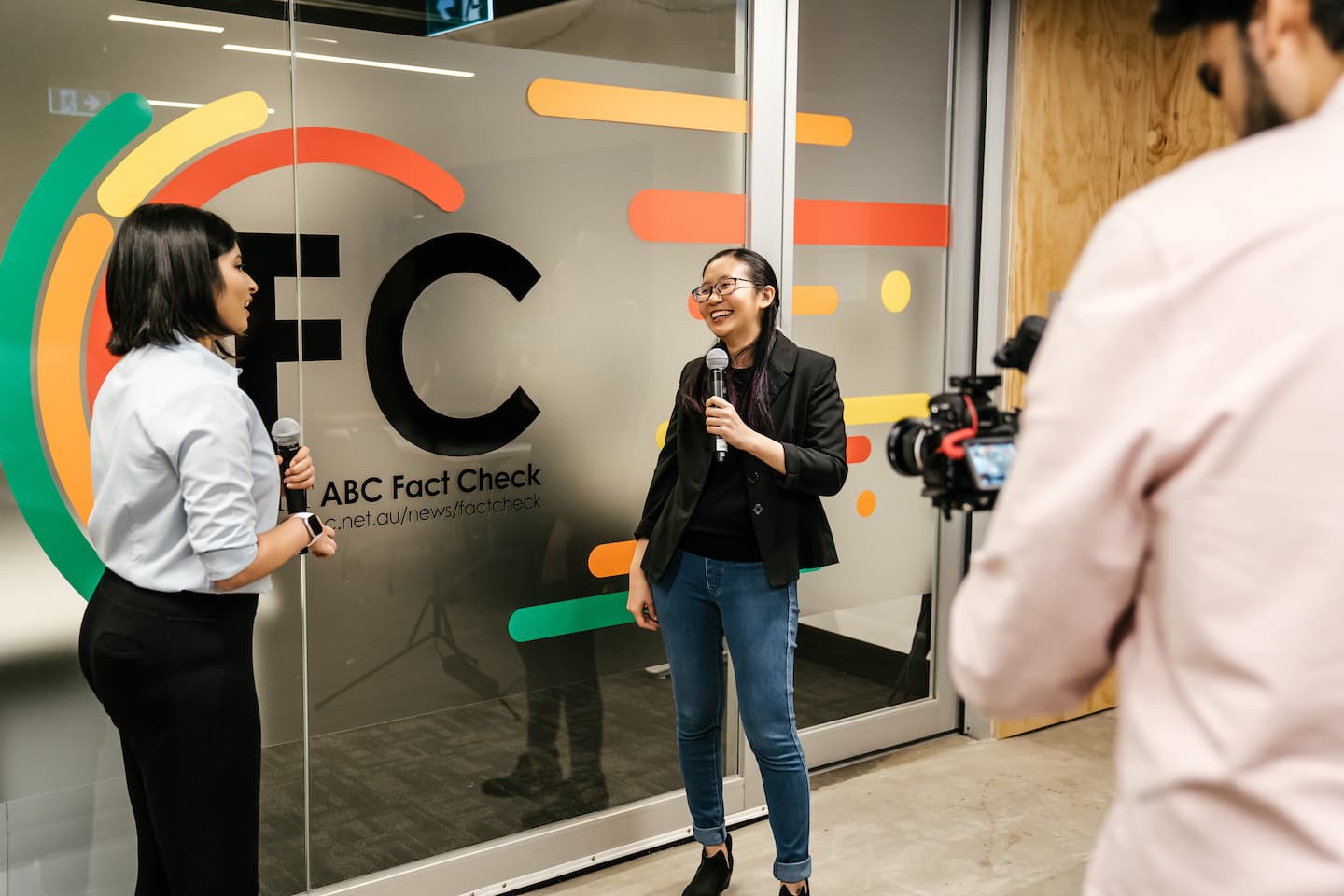 A reporter interviews a woman outside an office.