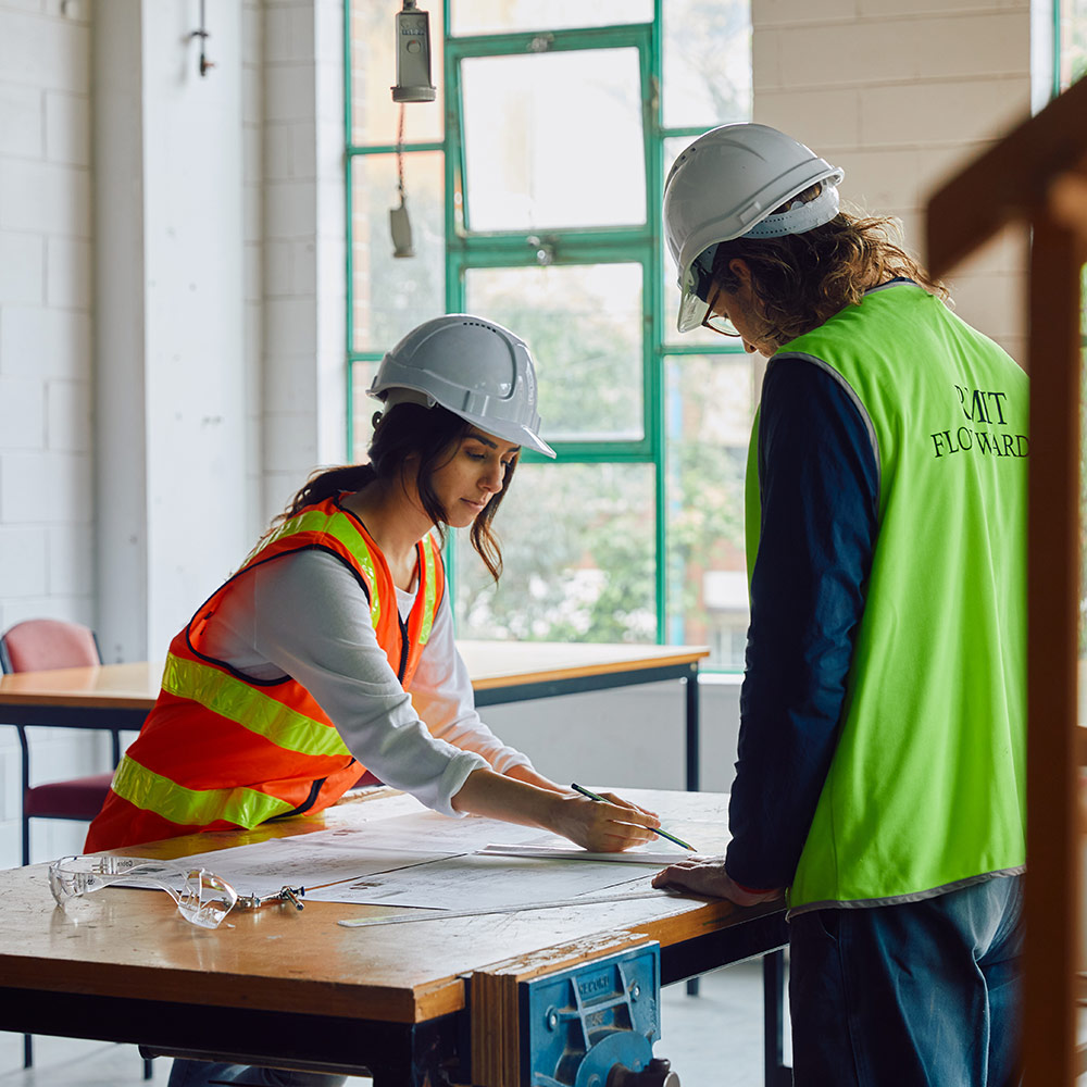 Two people in high visibility clothing working on a document