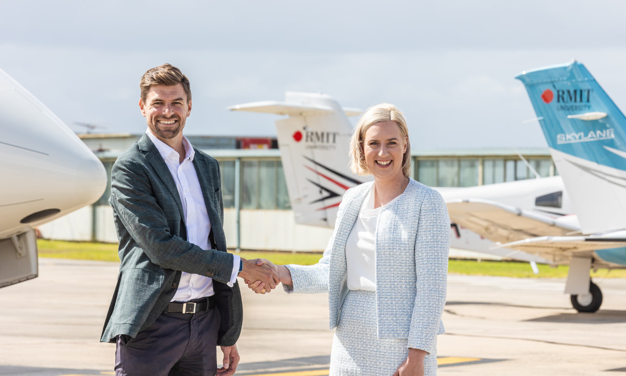 A man and a women shaking hands with planes in the background