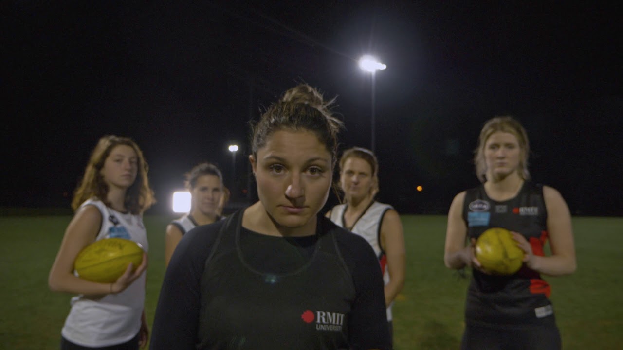 Five female football players on a field at night