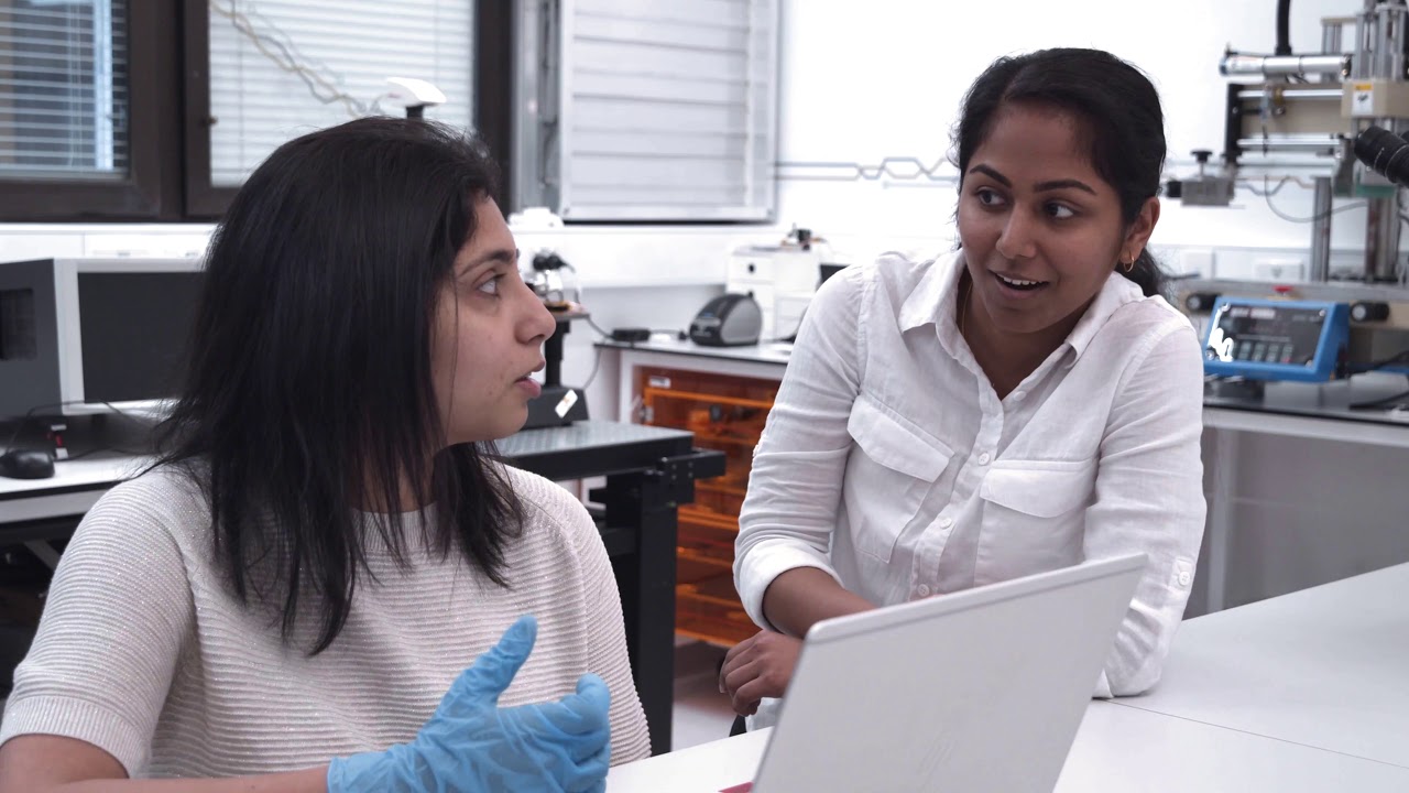 Two female students having a discussion in front of a laptop