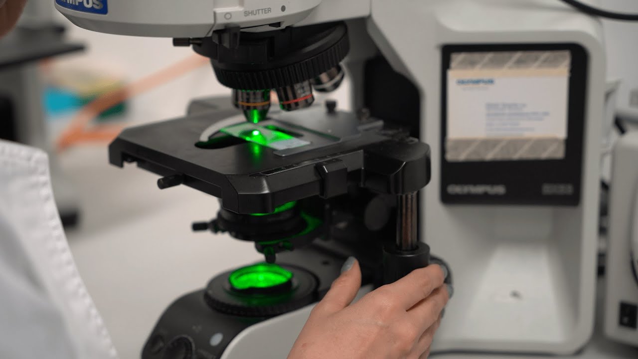 close up image of a hand operating a microscope in a laboratory