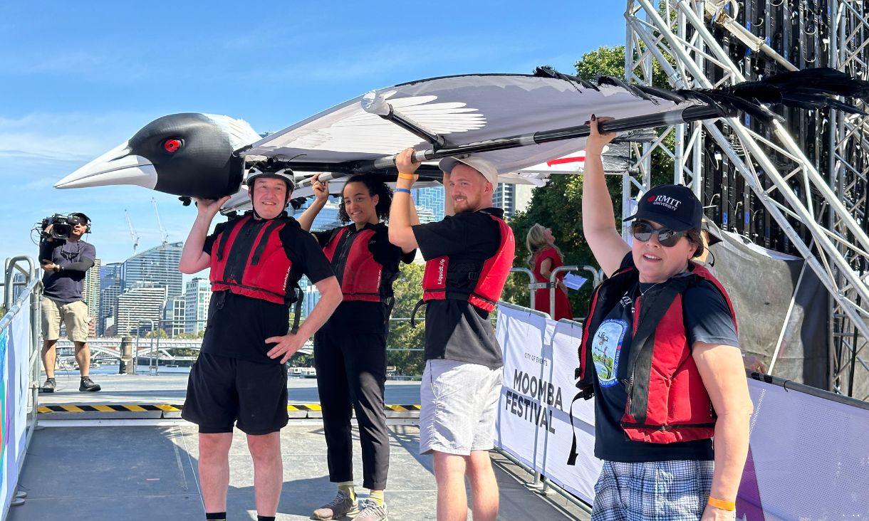 RMIT team and British Consul-General for Victoria, Stephen Lysaght, holding flying contraption overlooking Yarra.