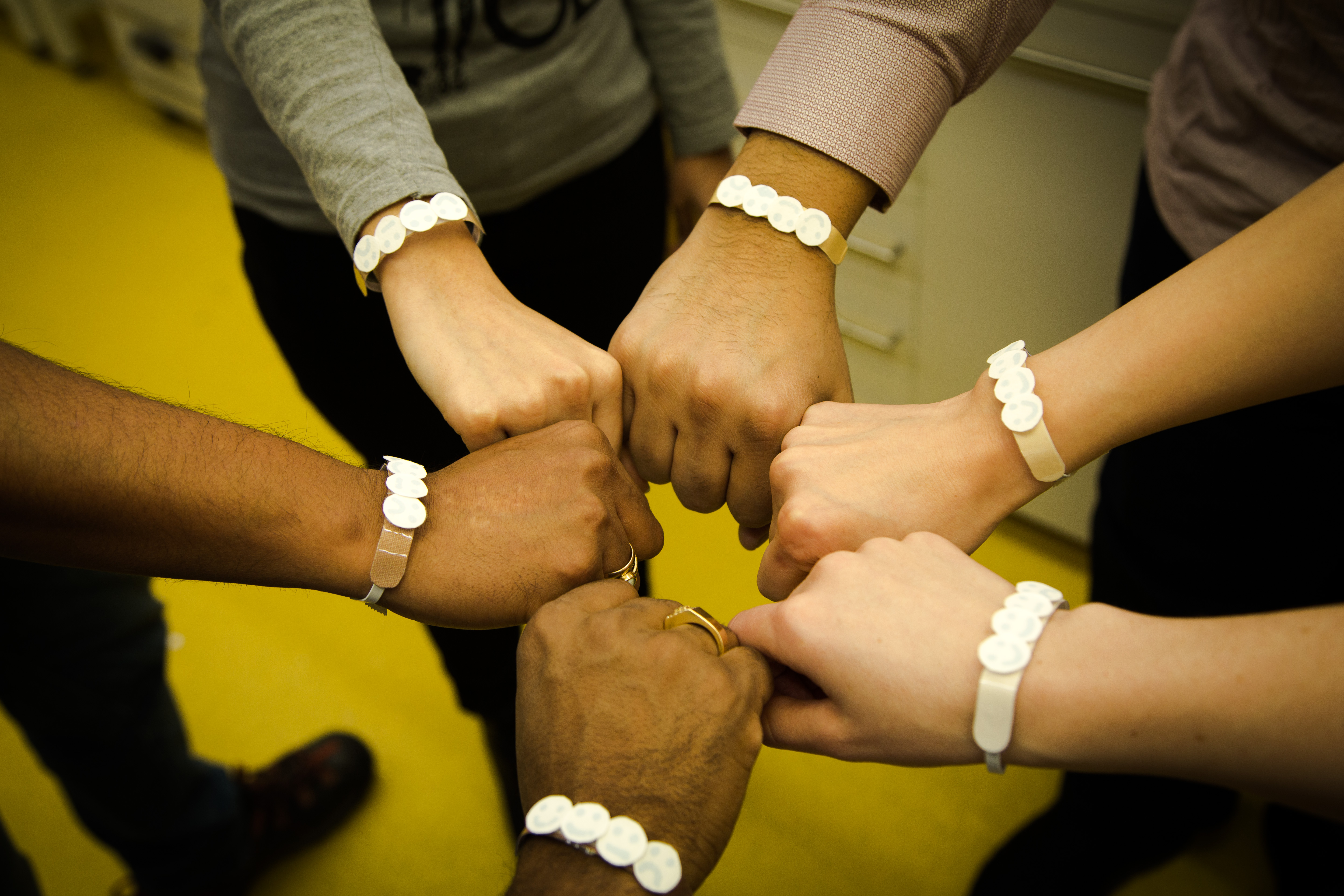 6 hands together in a circular fist-bump