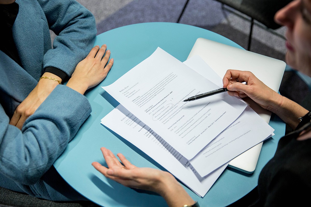 A student explains paperwork to another student.