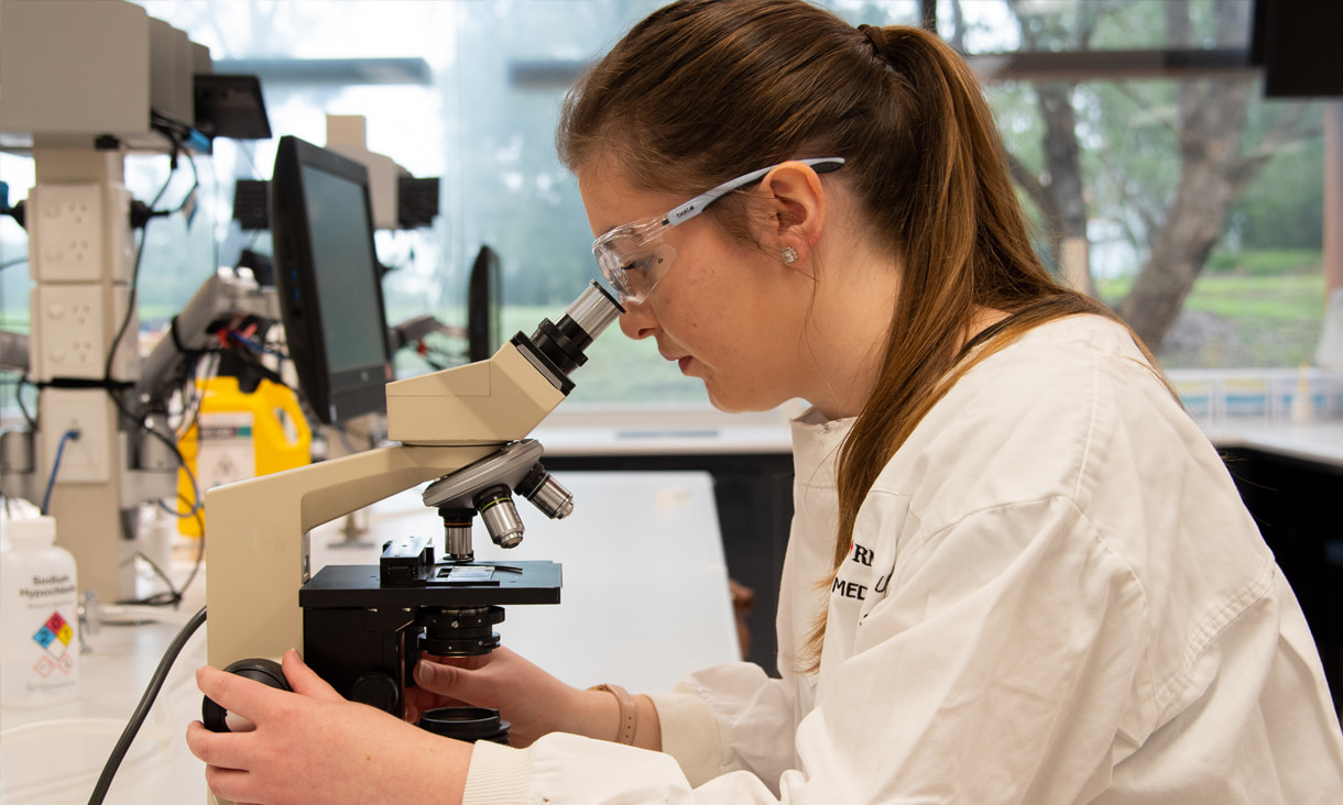 Young woman in a lab coat using a microscope