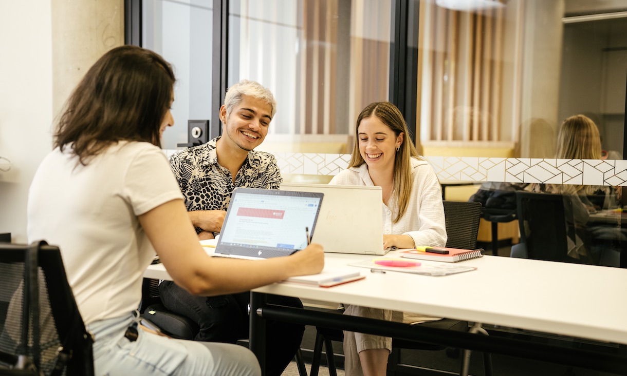 Three students study at the City Campus. All smile at their laptops.