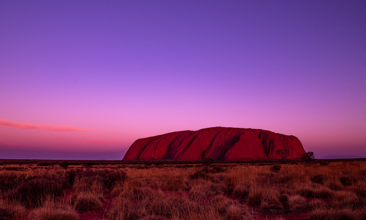 photo of uluru with purple sky in background