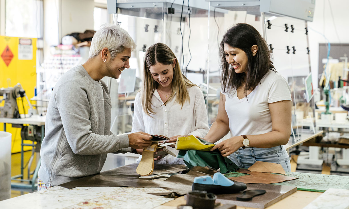 Three students around a textile cutting table